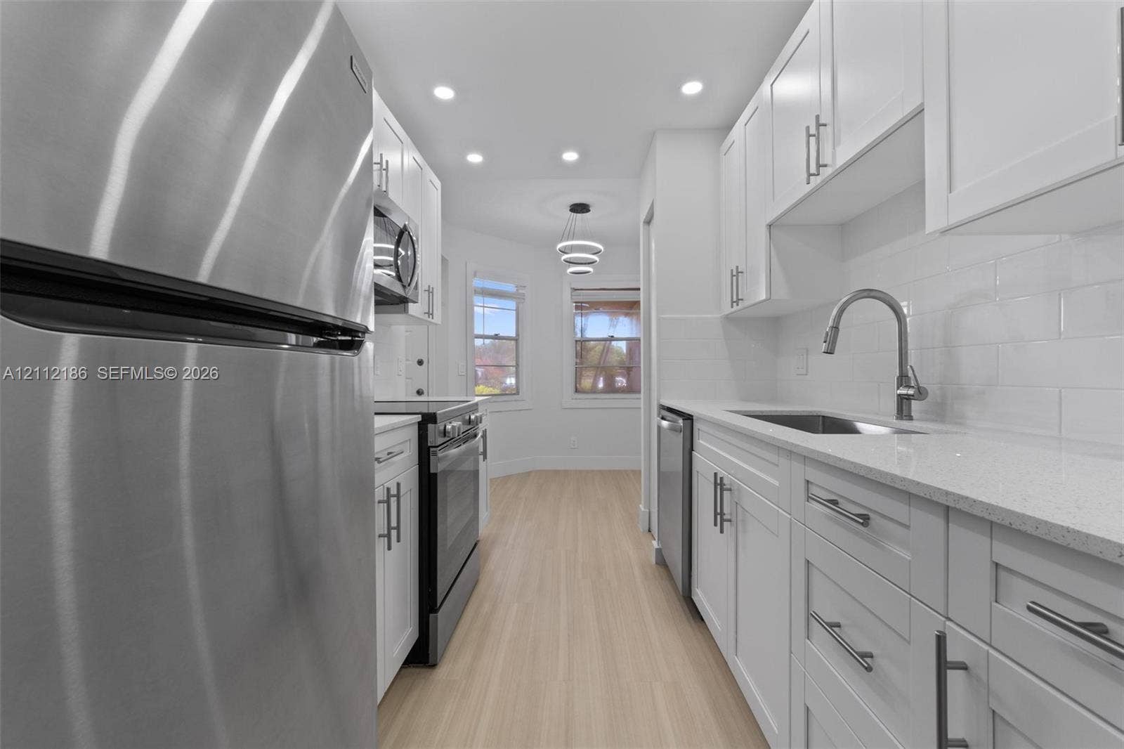 1300 SW 124th Terrace, #107P, Pembroke Pines, Pembroke Pines, FL 33027 Kitchen featuring white shaker-style cabinetry, quartz countertops, stainless steel appliances, white subway tile backsplash, and light-toned wood-finish flooring