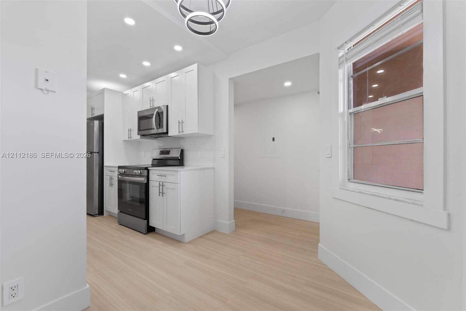 1300 SW 124th Terrace, #107P, Pembroke Pines, Pembroke Pines, FL 33027 Kitchen featuring white Shaker-style cabinetry, stainless steel appliances, light-toned wood-finish flooring, recessed lighting, and a modern circular chandelier
