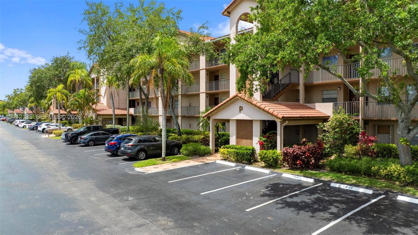 1300 SW 124th Terrace, #107P, Pembroke Pines, Pembroke Pines, FL 33027 Multi-story residential building featuring a tile roof, private balcony access, covered parking entry, and established landscaping