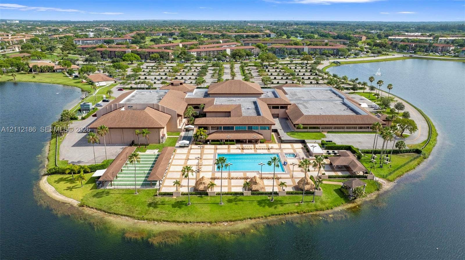 1300 SW 124th Terrace, #107P, Pembroke Pines, Pembroke Pines, FL 33027 Waterfront property featuring a paved pool deck, swimming pool, shuffleboard court, and mature palm trees