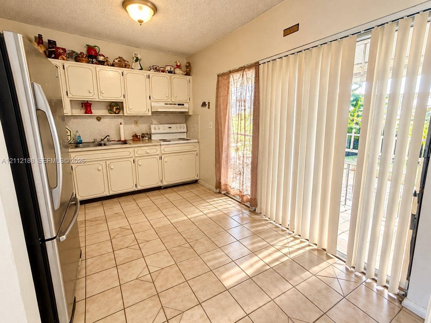 2445 SW 19th Street, Miami, FL 33145 Kitchen featuring white cabinetry, stainless steel refrigerator, white electric range, tile flooring, and floor-to-ceiling sliding glass doors