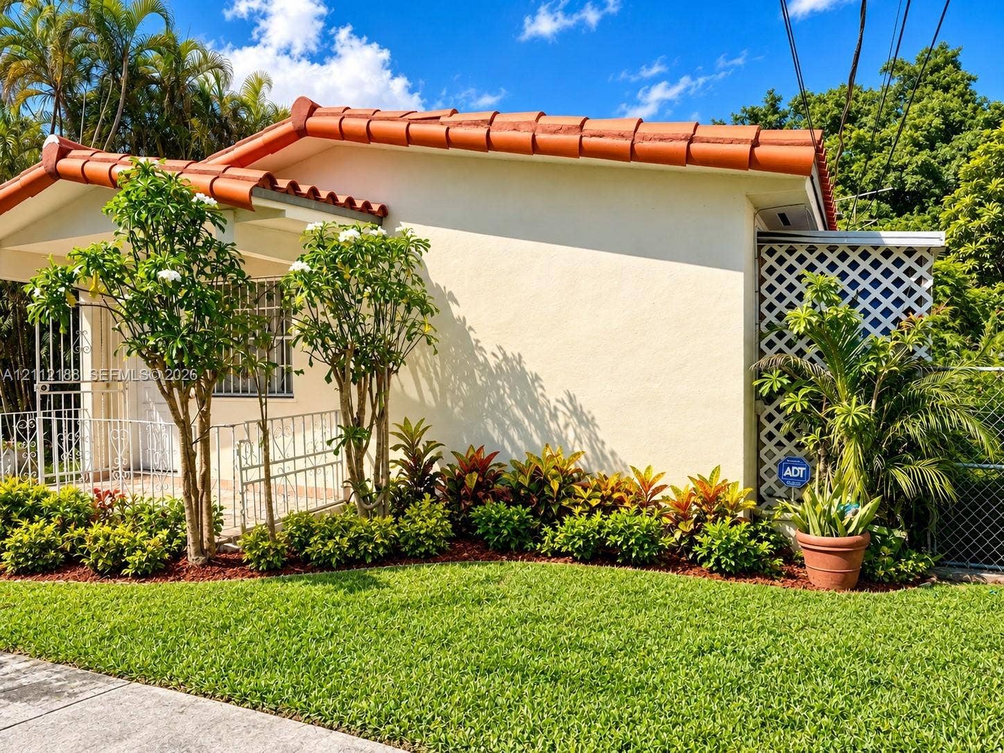 2445 SW 19th Street, Miami, FL 33145 Stucco exterior featuring a terracotta tile roof, decorative metal front door security screen, and landscaped garden beds