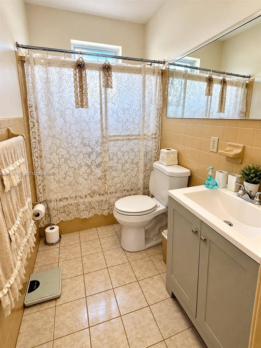 2445 SW 19th Street, Miami, FL 33145 Bathroom featuring square tile flooring, wall-mounted mirror, vanity cabinet with integrated sink, and tile-surround shower area