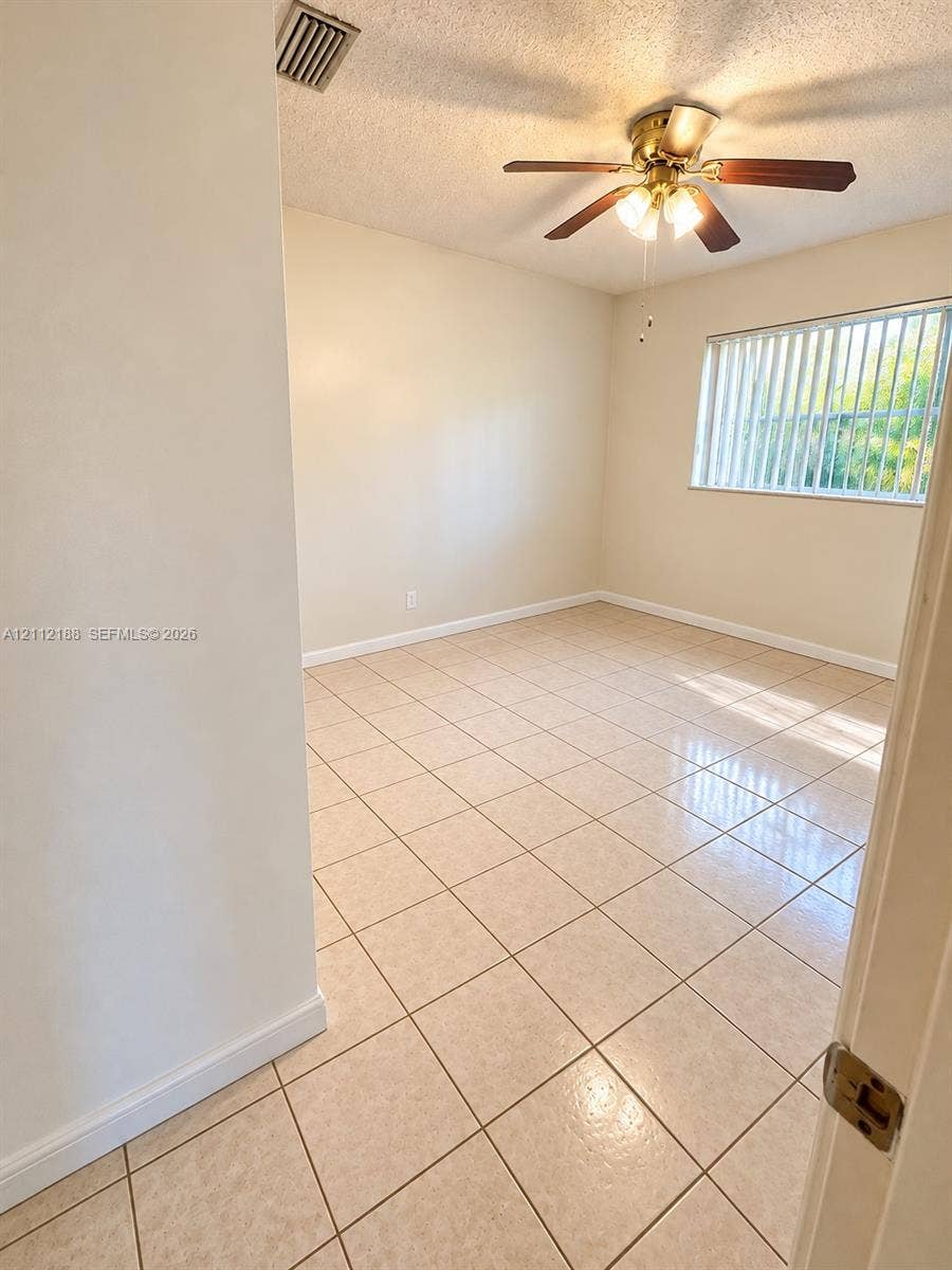 2445 SW 19th Street, Miami, FL 33145 Neutral-toned tile flooring, multi-blade ceiling fan with integrated light fixture, and horizontal window blinds