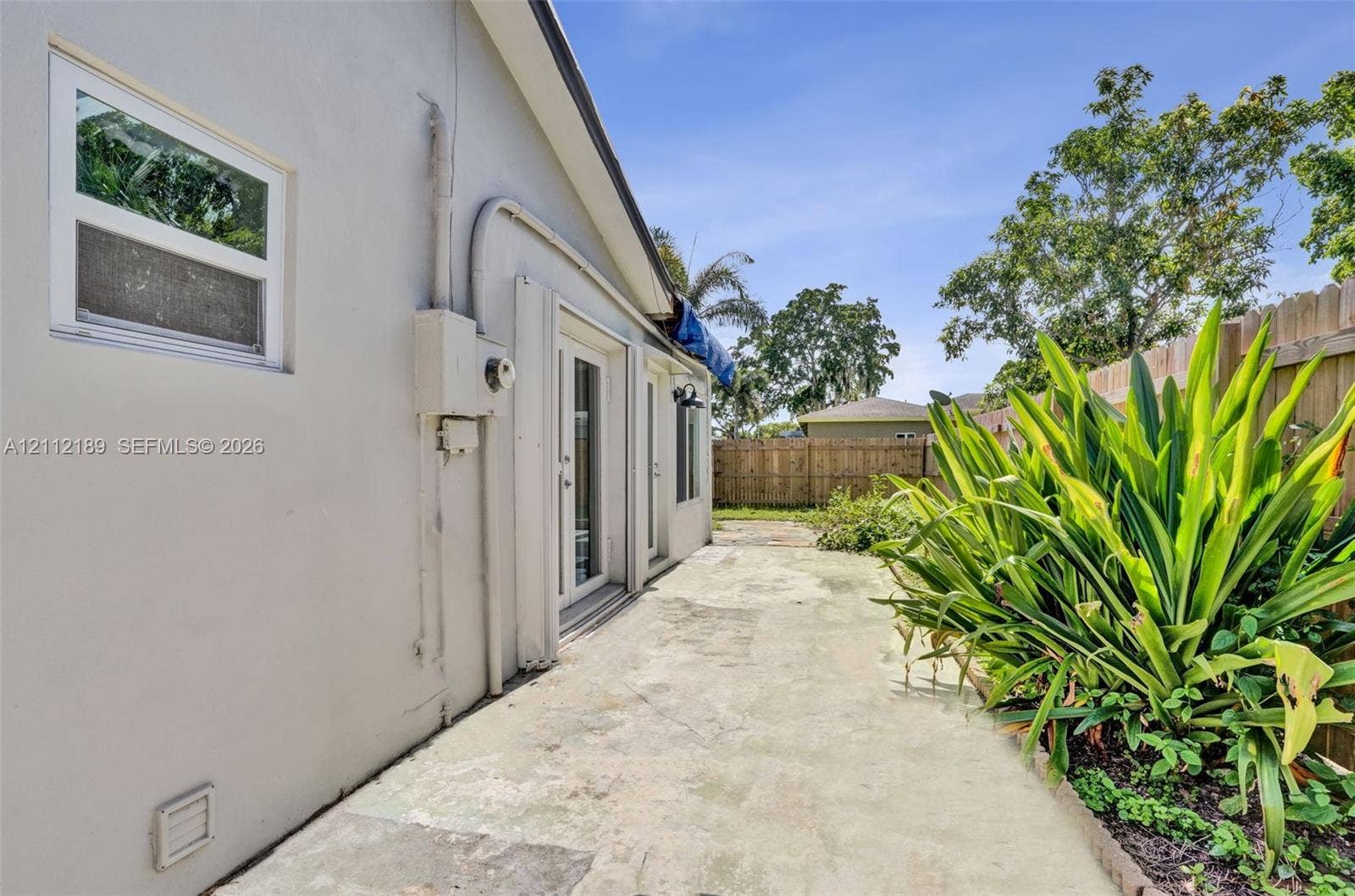 5161 SW 7th Court, #0, Margate, Margate, FL 33068 Concrete patio featuring dual glass-panel exterior doors, stucco siding, and a wooden privacy fence