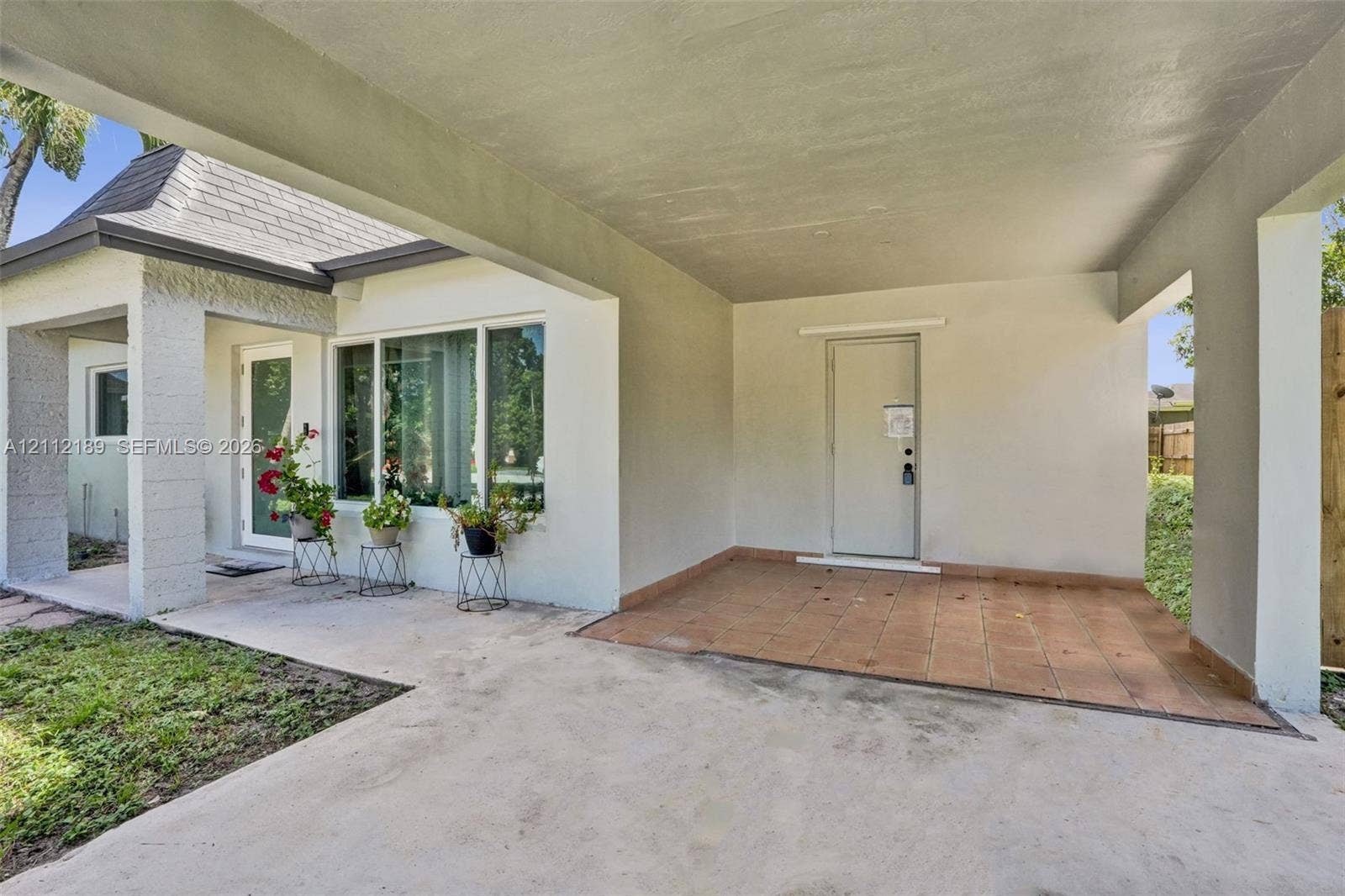 5161 SW 7th Court, #0, Margate, Margate, FL 33068 Covered carport featuring neutral-toned stucco exterior, terracotta-style tiled flooring, and multiple large windows