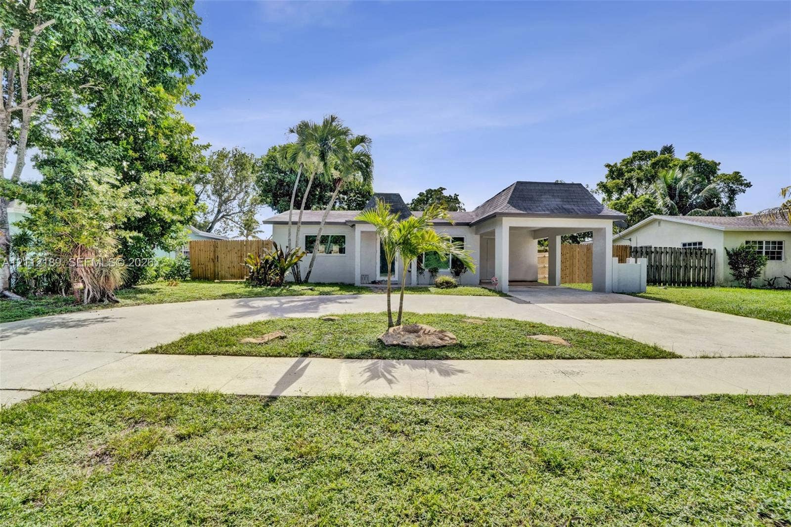 5161 SW 7th Court, #0, Margate, Margate, FL 33068 Single-story exterior featuring a hip roof, a concrete circular driveway, an attached carport, and mature palm trees