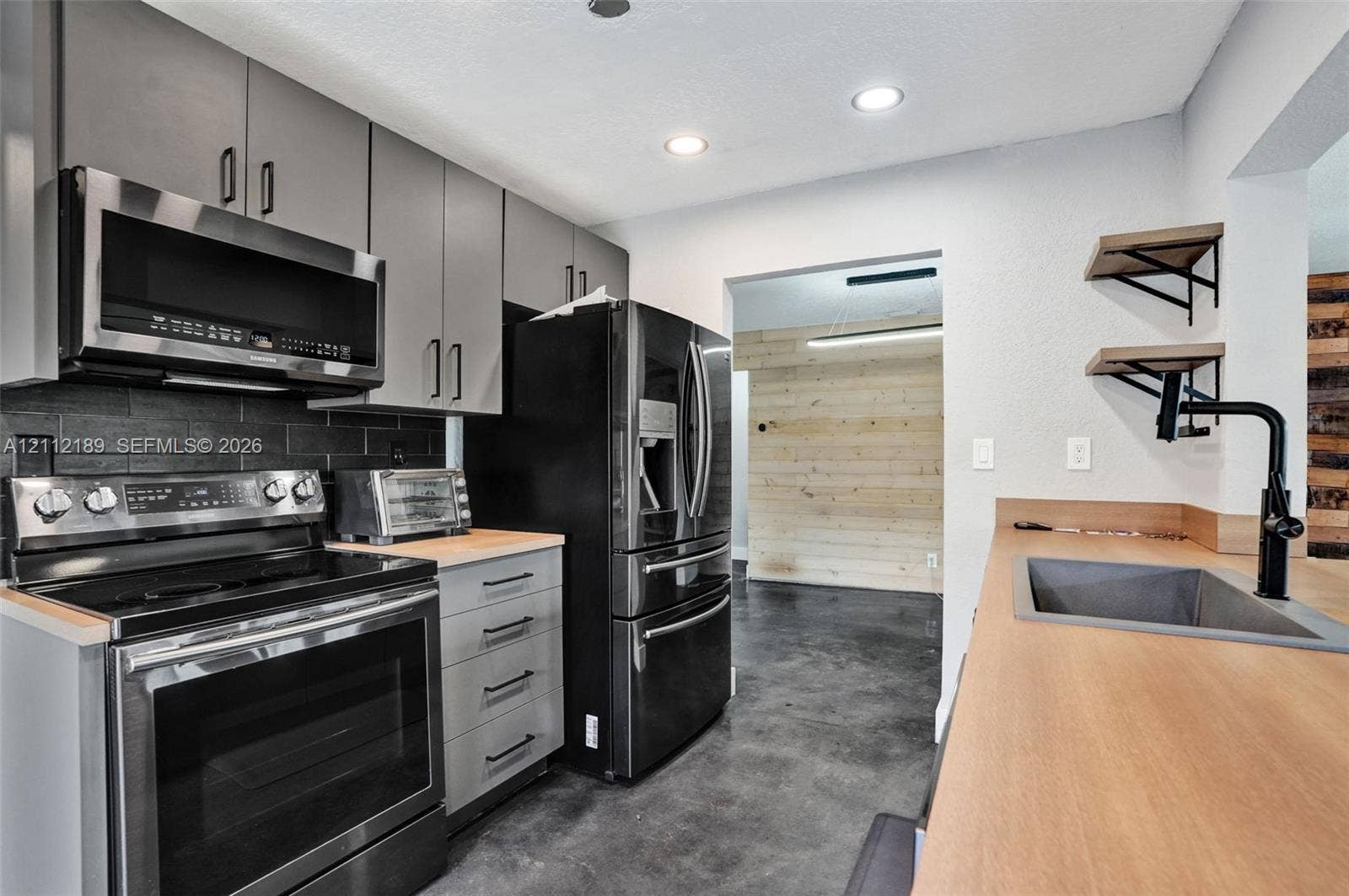 5161 SW 7th Court, #0, Margate, Margate, FL 33068 Kitchen featuring gray flat-panel cabinetry, dark brick-style backsplash, integrated stainless steel appliances, wood-finish countertops, and matte black plumbing fixtures