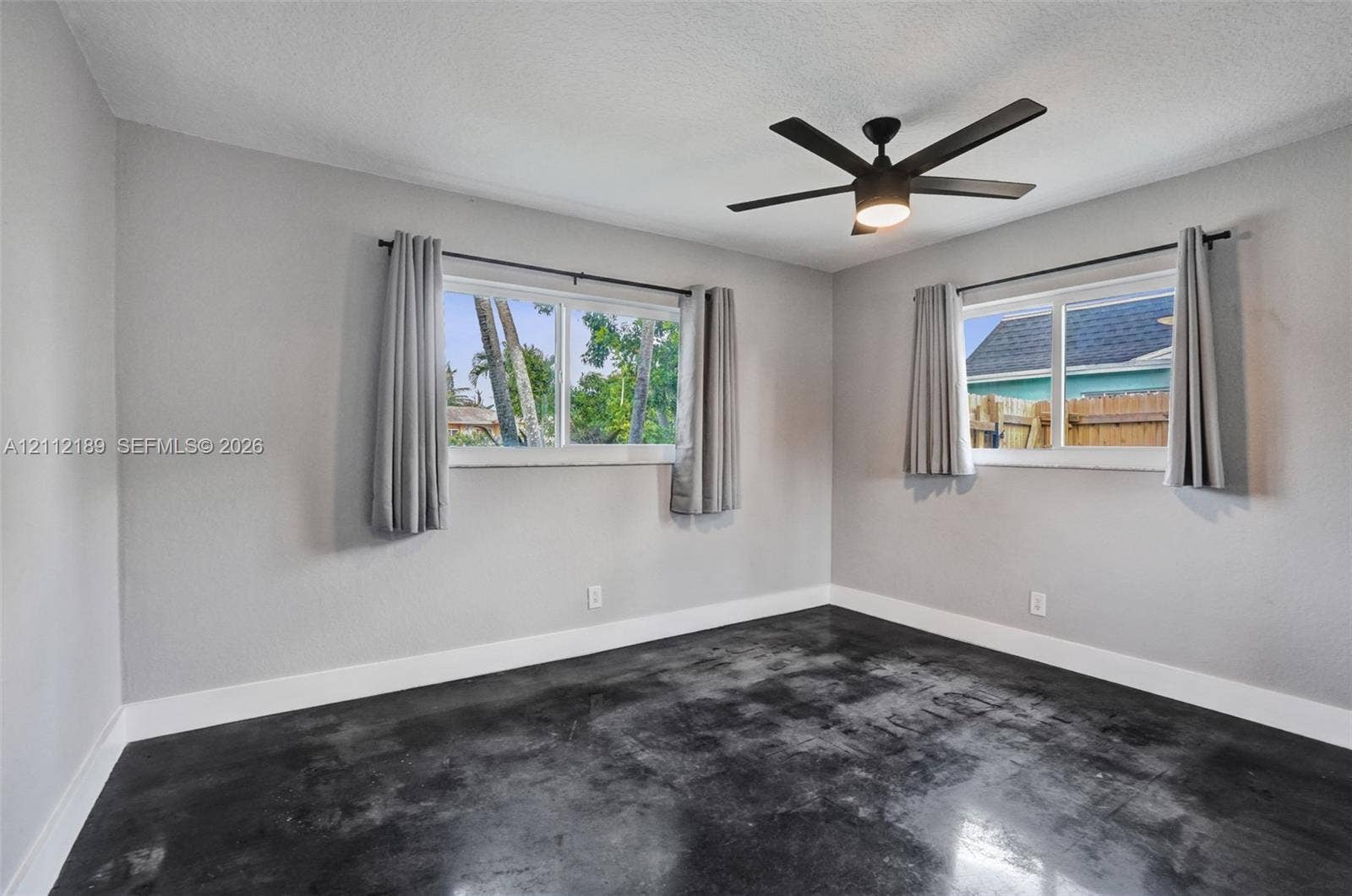 5161 SW 7th Court, #0, Margate, Margate, FL 33068 Interior space featuring stained concrete flooring, neutral wall tones, sliding windows, and a matte black ceiling fan