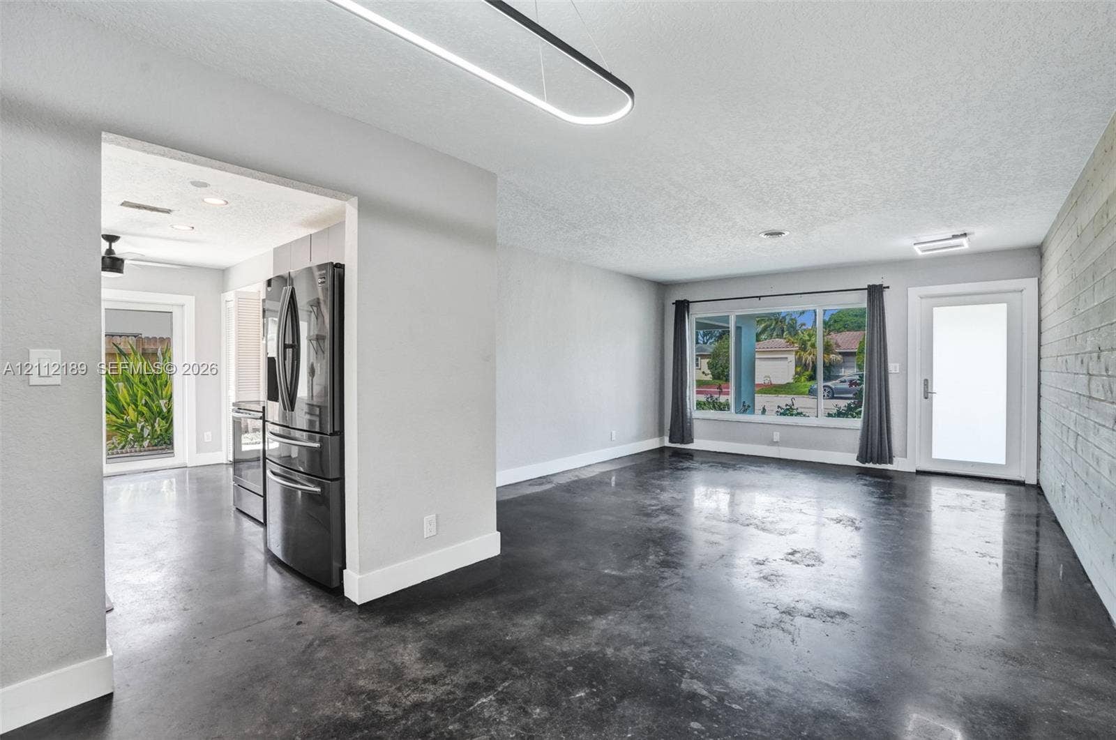 5161 SW 7th Court, #0, Margate, Margate, FL 33068 Polished concrete flooring, linear pendant lighting, built-in stainless steel refrigerator, textured wood-plank accent wall, and large picture window