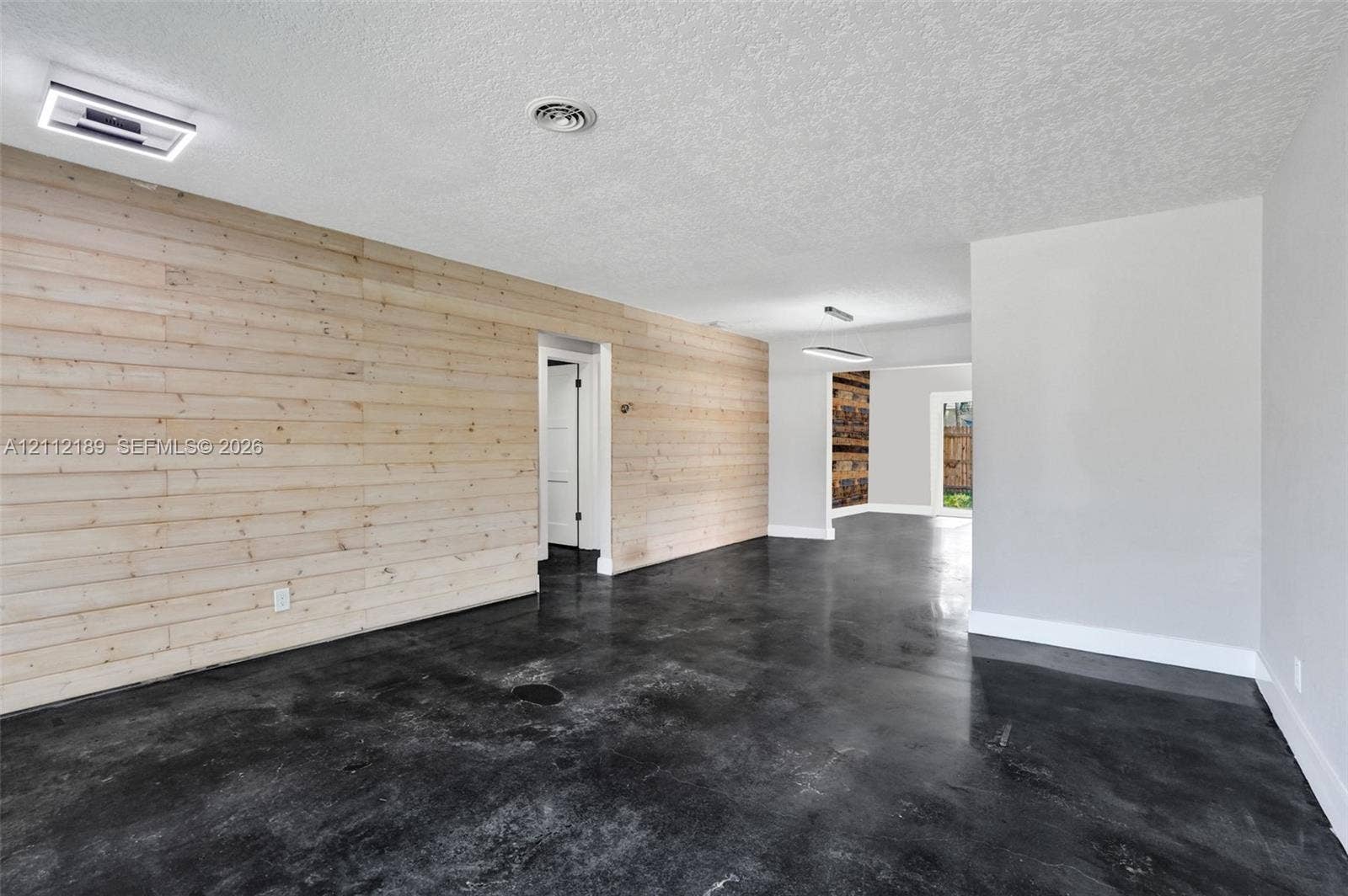 5161 SW 7th Court, #0, Margate, Margate, FL 33068 Interior space featuring horizontal light wood-plank wall paneling, polished concrete flooring, flush-mount LED lighting, and textured ceilings
