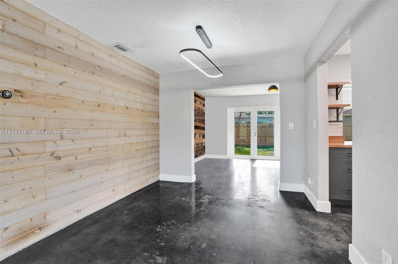 5161 SW 7th Court, #0, Margate, Margate, FL 33068 Interior space featuring horizontal natural wood-finish wall paneling, polished concrete flooring, a contemporary oval LED light fixture, and double glass-paned doors