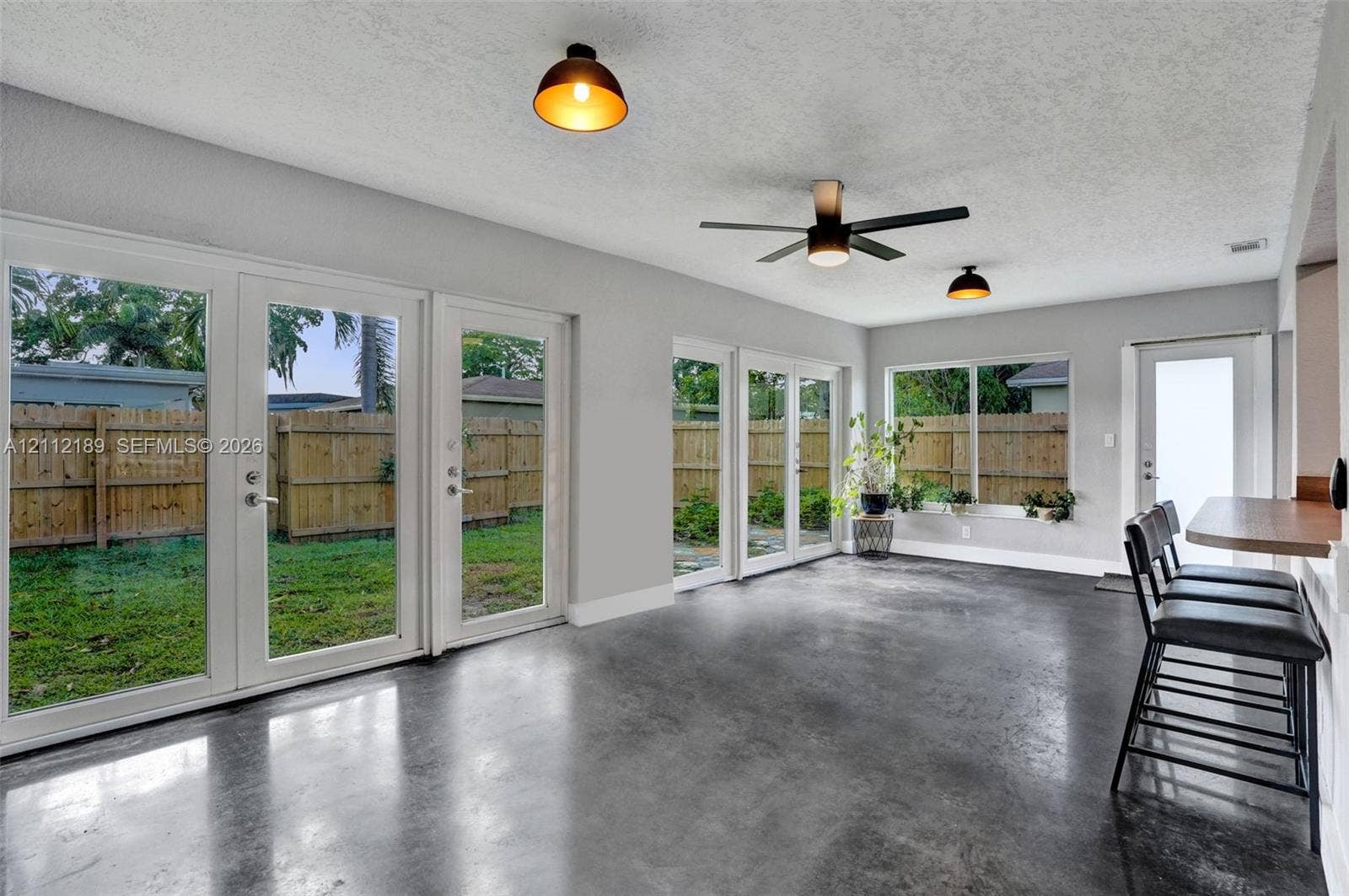 5161 SW 7th Court, #0, Margate, Margate, FL 33068 Polished concrete flooring, multiple glass-paneled exterior doors, a built-in breakfast bar, and industrial-style dome pendant lighting
