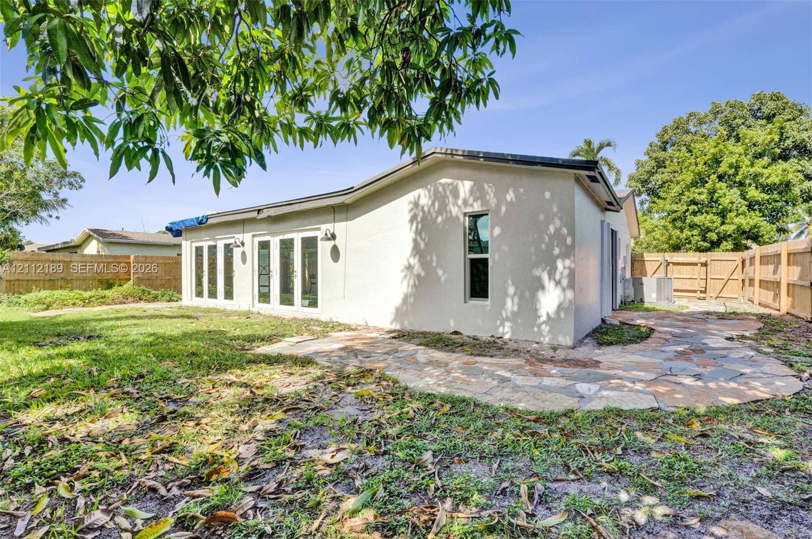 5161 SW 7th Court, #0, Margate, Margate, FL 33068 Stucco exterior featuring multiple sets of white-framed glass doors, a flagstone patio, and wood-panel fencing