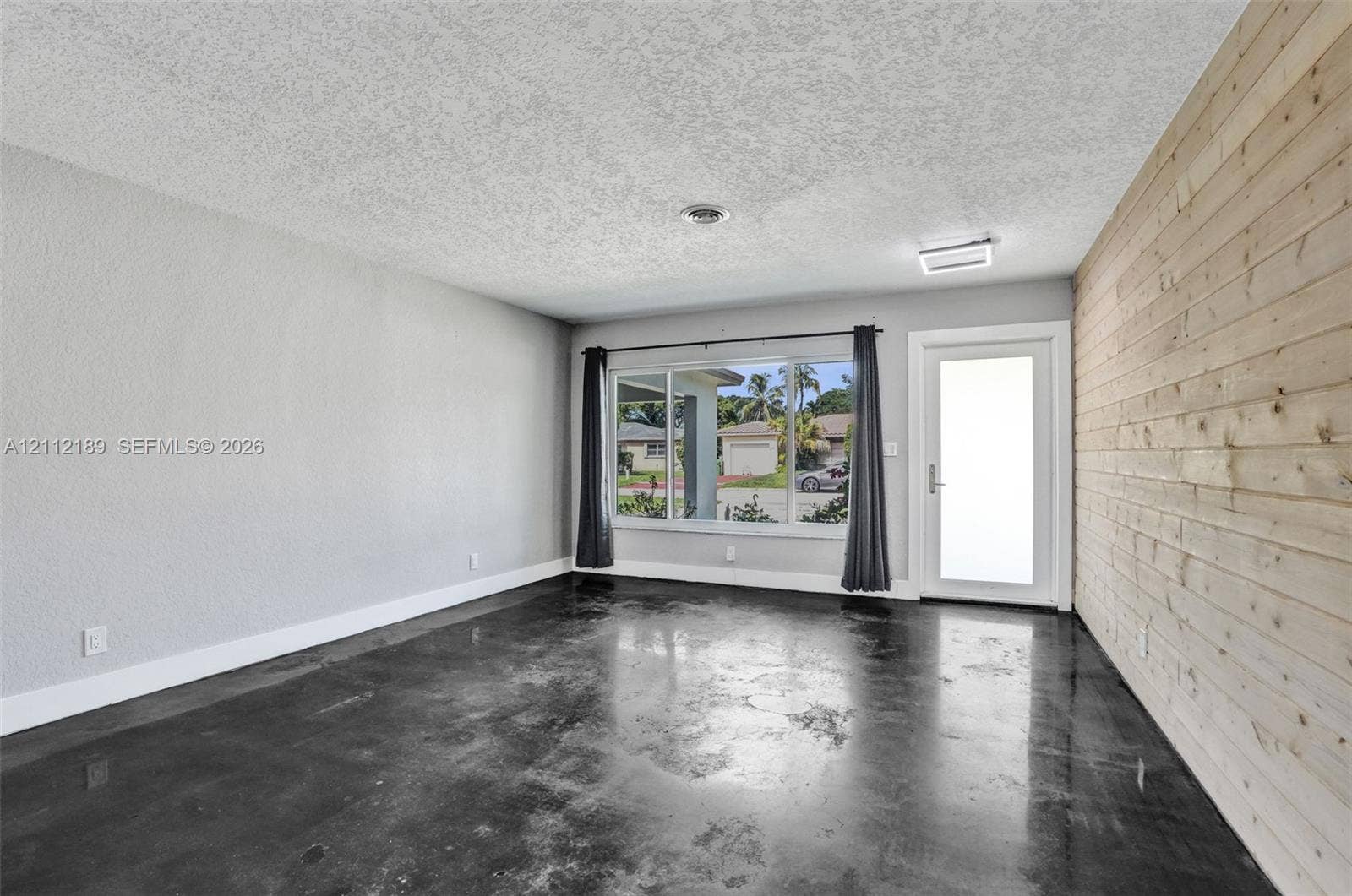 5161 SW 7th Court, #0, Margate, Margate, FL 33068 Polished concrete flooring, horizontal wood-plank accent wall, large picture window, and exterior door with frosted glass insert