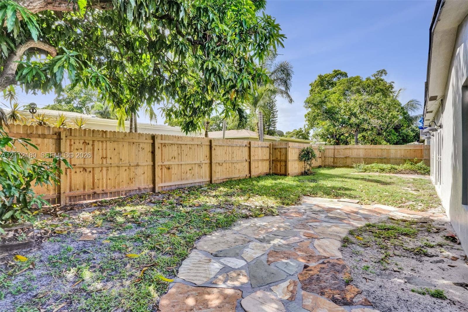 5161 SW 7th Court, #0, Margate, Margate, FL 33068 Private backyard featuring a natural stone pathway, wood-style privacy fencing, and mature trees