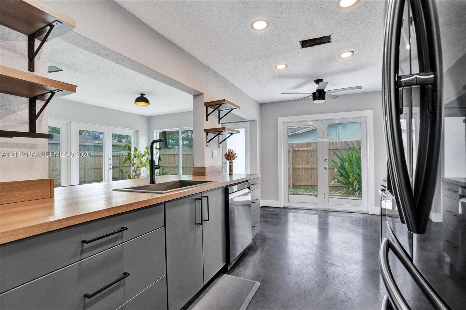 5161 SW 7th Court, #0, Margate, Margate, FL 33068 Kitchen featuring matte gray cabinetry, butcher block countertops, open wall-mounted shelving, polished concrete flooring, and stainless steel dishwasher