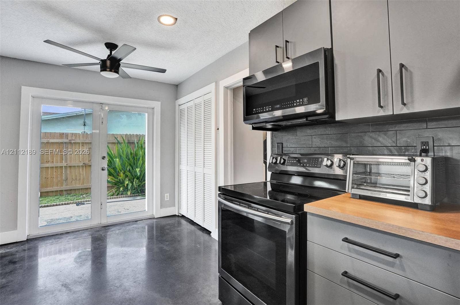5161 SW 7th Court, #0, Margate, Margate, FL 33068 Kitchen featuring grey cabinetry, butcher-block countertops, dark tile backsplash, polished concrete flooring, and double glass-pane doors