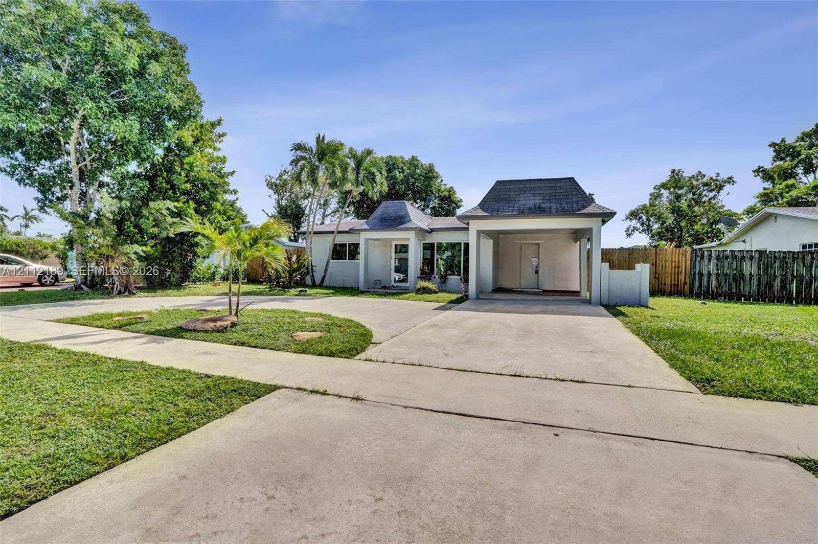 5161 SW 7th Court, #0, Margate, Margate, FL 33068 Single-story residence featuring a covered carport, pitched shingle roofline, concrete driveway, and expansive lawn with mature palm trees
