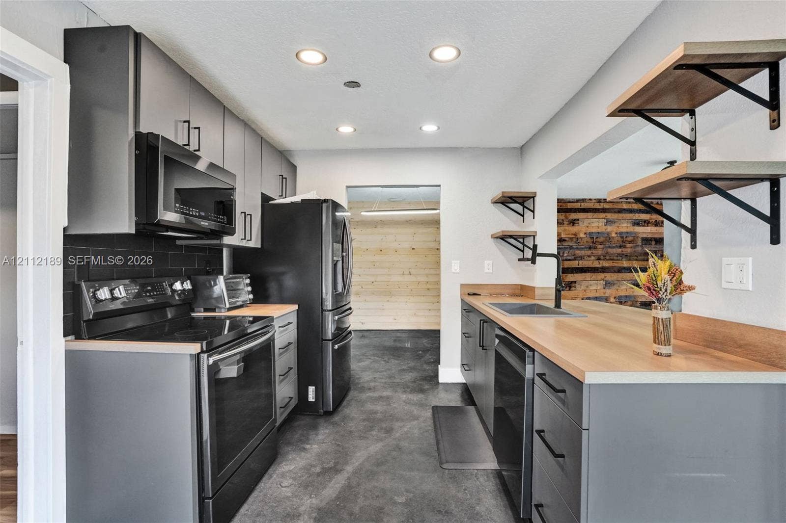 5161 SW 7th Court, #0, Margate, Margate, FL 33068 Kitchen featuring matte grey cabinetry, wood-finish countertops, black subway tile backsplash, integrated black appliances, and industrial-style open shelving