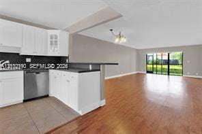 440 Lakeview Drive, #103, Weston, Weston, FL 33326 Kitchen featuring white shaker-style cabinetry, stainless steel dishwasher, dark stone-finish countertops, wood-finish flooring, and floor-to-ceiling glass sliding doors