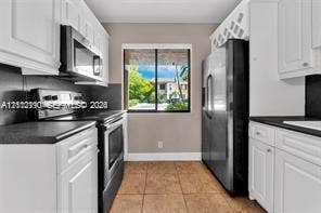 440 Lakeview Drive, #103, Weston, Weston, FL 33326 Kitchen featuring white shaker-style cabinetry, dark stone-finish countertops, stainless steel appliances, a built-in wine rack, and tile flooring