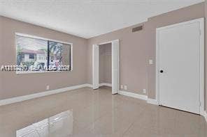 440 Lakeview Drive, #103, Weston, Weston, FL 33326 Neutral-toned interior featuring large-format tile flooring, a horizontal sliding window with blinds, and a built-in closet with double doors