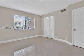 440 Lakeview Drive, #103, Weston, Weston, FL 33326 Neutral-toned interior featuring large-format tile flooring, a horizontal sliding window, and a dual-panel closet door