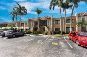 440 Lakeview Drive, #103, Weston, Weston, FL 33326 Two-story exterior featuring a clay tile roof, screened-in balconies, stucco siding, and mature palm trees