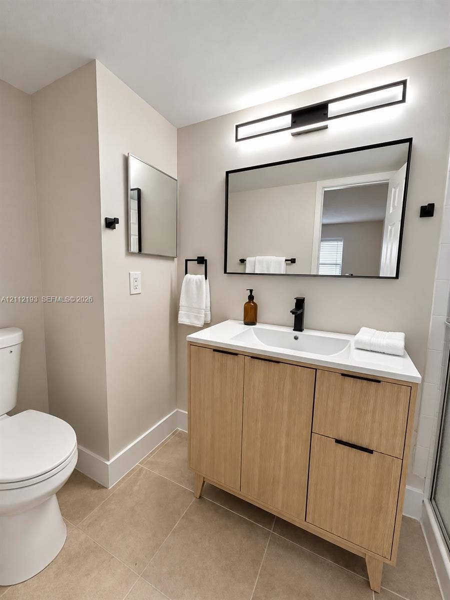 10013 Winding Lake Road, #106, Sunrise, Sunrise, FL 33351 Modern light wood-finish vanity with a rectangular integrated sink, neutral stone-composite countertop, matte black faucet, and matching framed mirror with integrated LED light fixture