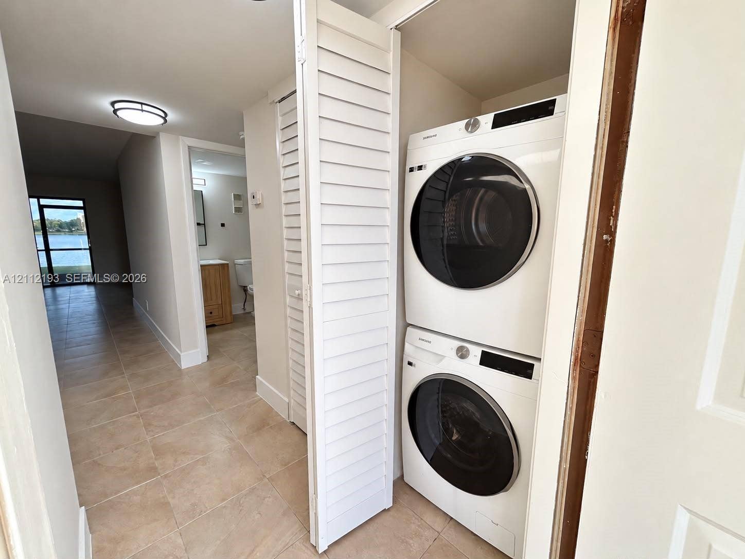10013 Winding Lake Road, #106, Sunrise, Sunrise, FL 33351 Stacked laundry appliance set housed within a closet featuring white louvered doors