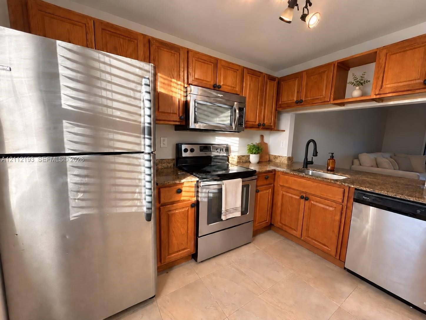 10013 Winding Lake Road, #106, Sunrise, Sunrise, FL 33351 Kitchen featuring wood cabinetry, stone countertops, stainless steel appliances, a deep-basin sink with a matte black faucet, and tile flooring