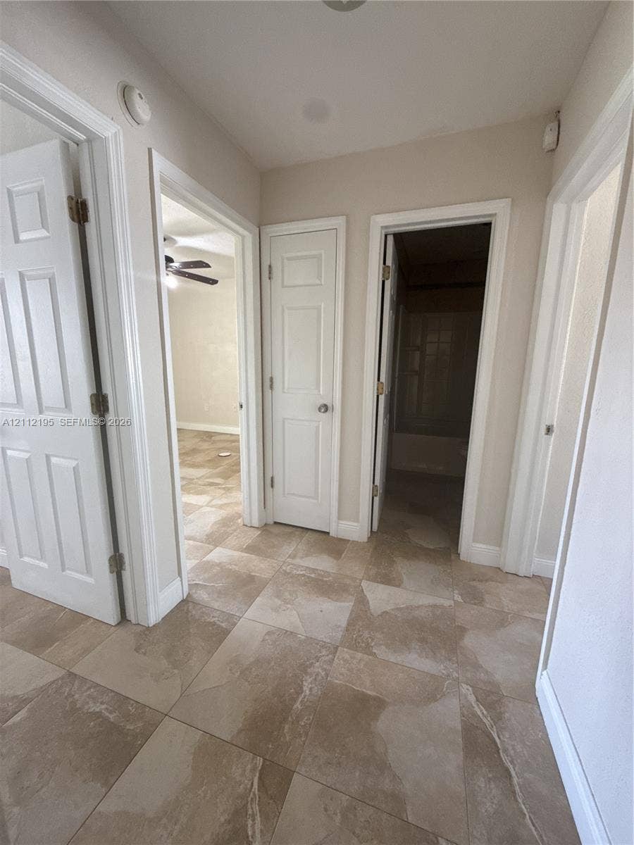 11745 SW 122nd Place, #11745, Miami, Miami, FL 33186 Hallway featuring large-format ceramic tile flooring, neutral wall paint, and traditional six-panel interior doors