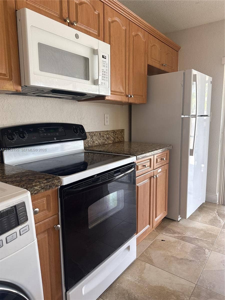 11745 SW 122nd Place, #11745, Miami, Miami, FL 33186 Kitchen featuring shaker-style wood cabinetry, stone-surface countertops, built-in white appliances, and tile flooring