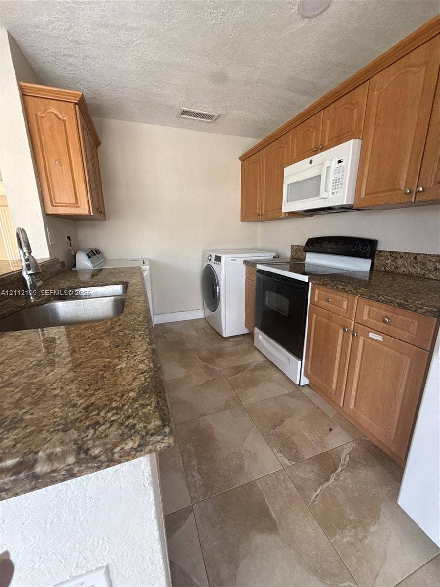 11745 SW 122nd Place, #11745, Miami, Miami, FL 33186 Kitchen featuring wood cabinetry, stone-finish countertops, tile flooring, dual-basin stainless steel sink, and built-in appliances