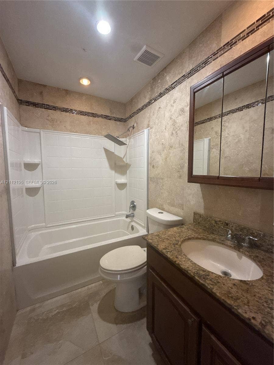 11745 SW 122nd Place, #11745, Miami, Miami, FL 33186 Bathroom featuring stone-finish wall tiling with mosaic accent borders, a built-in vanity with an integrated basin, a stone-finish countertop, and a rainfall showerhead