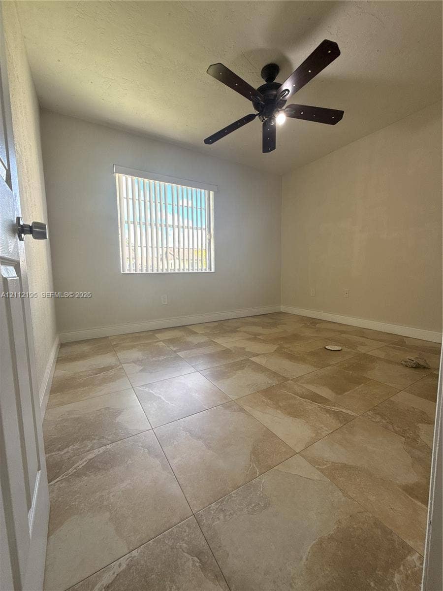 11745 SW 122nd Place, #11745, Miami, Miami, FL 33186 Neutral-toned large-format tile flooring, multi-blade ceiling fan with integrated lighting, and vertical window blinds