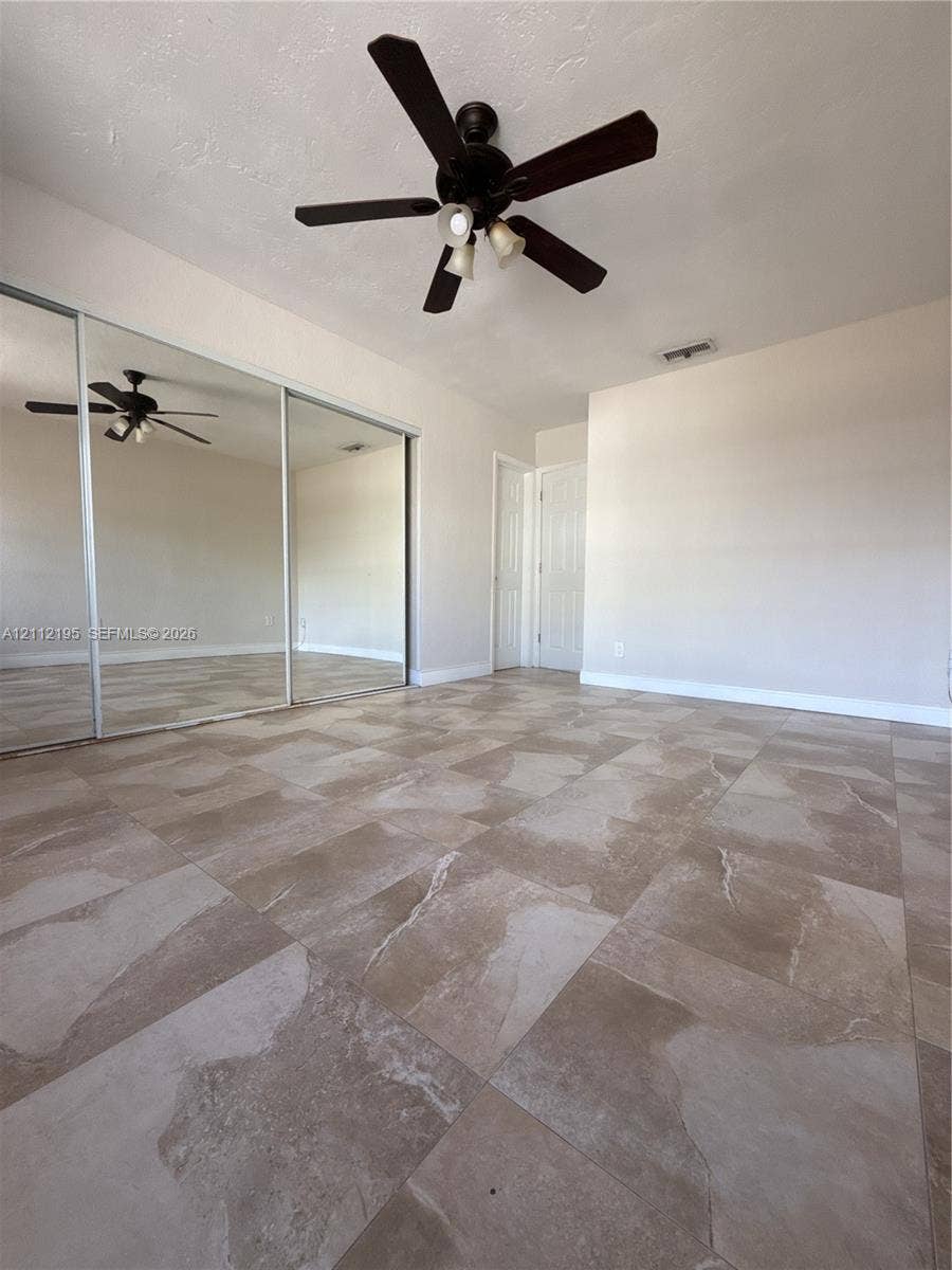 11745 SW 122nd Place, #11745, Miami, Miami, FL 33186 Large-format tile flooring, ceiling fan with integrated lighting, and wall-to-wall sliding mirrored closet doors