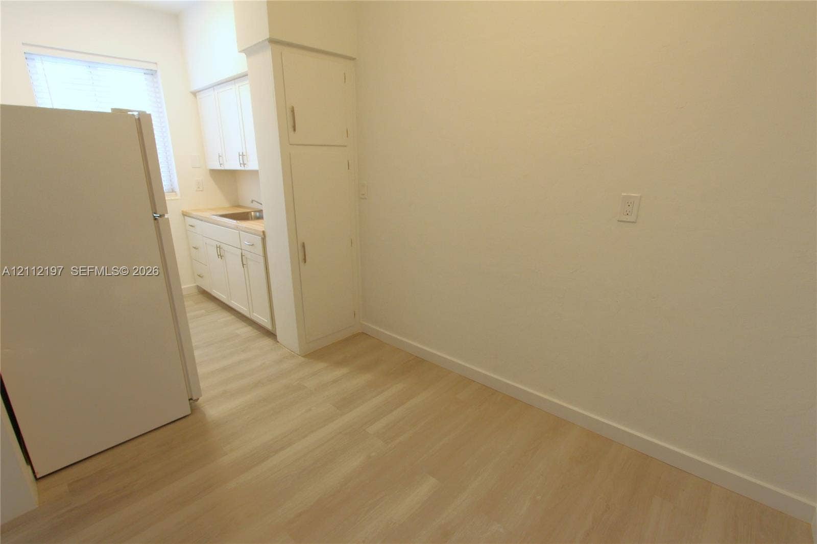 1115 Euclid Avenue, #15, Miami Beach, Miami Beach, FL 33139 Kitchen featuring wood-finish flooring, white cabinetry with integrated storage, and a stainless steel sink