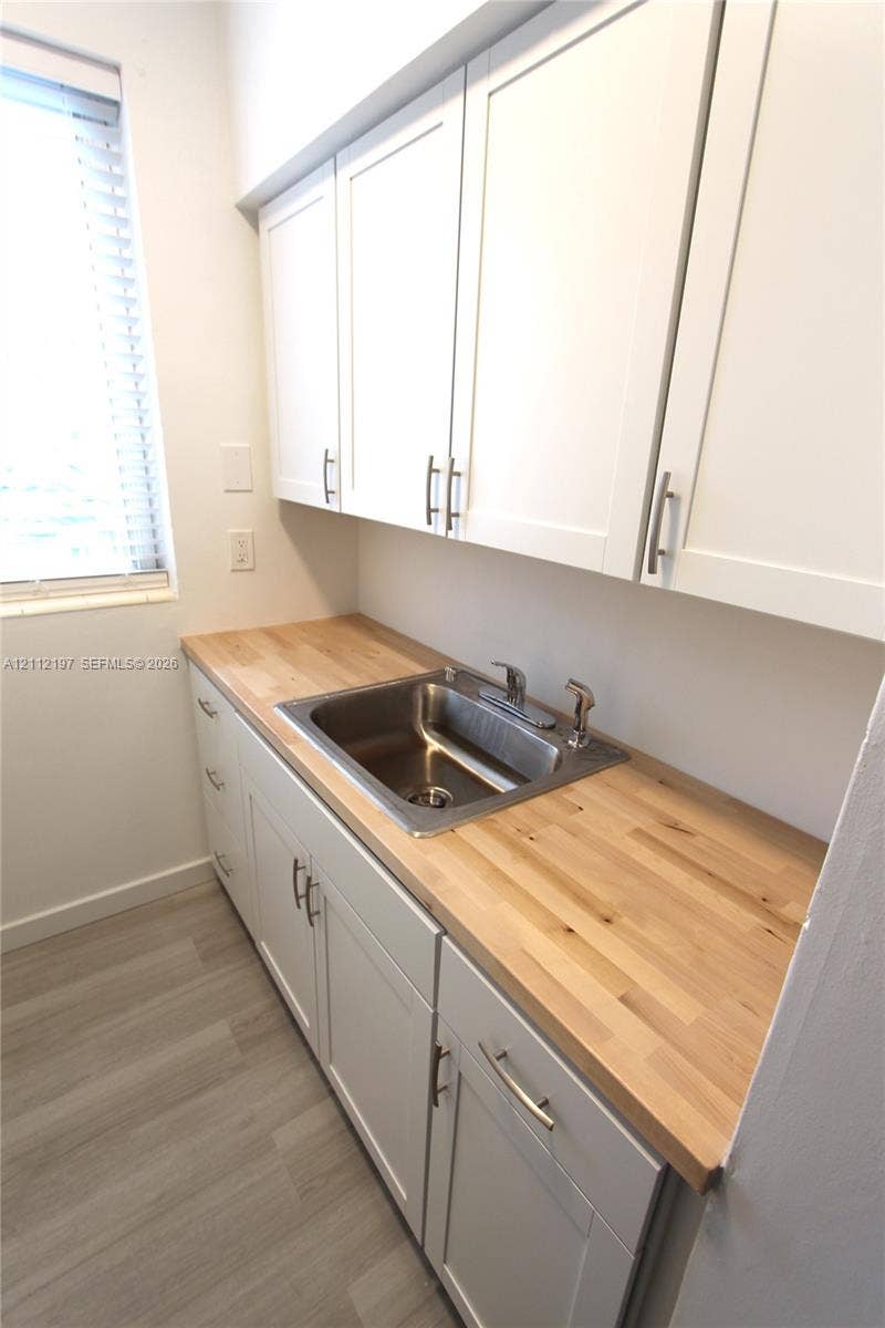 1115 Euclid Avenue, #15, Miami Beach, Miami Beach, FL 33139 White shaker-style cabinetry with metallic pulls, butcher-block countertop, stainless steel undermount sink, and wood-finish flooring