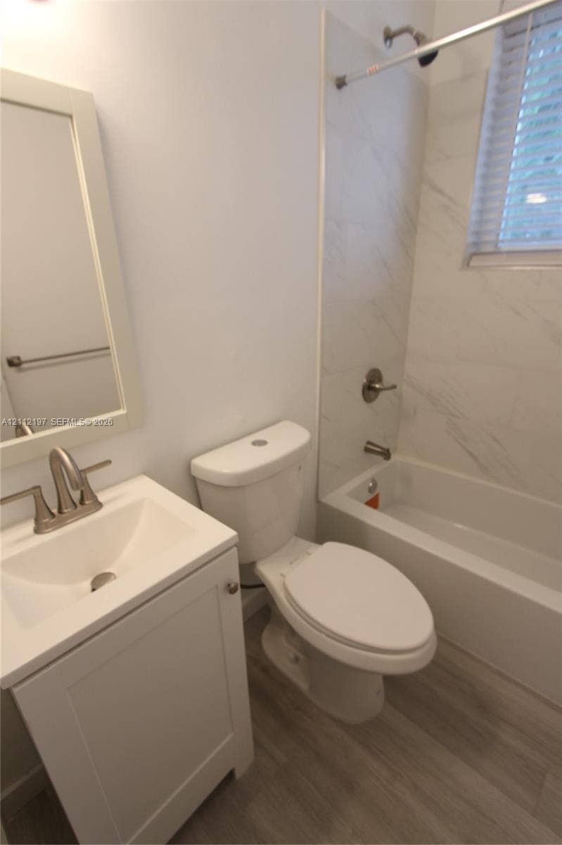 1115 Euclid Avenue, #15, Miami Beach, Miami Beach, FL 33139 Bathroom featuring a single-sink vanity with a rectangular basin, wood-finish flooring, and a tub-shower combination with light-toned wall tile