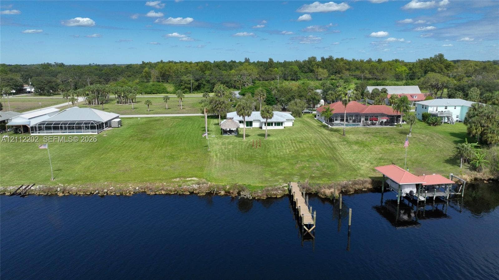 3233 Shell Lane, Labelle, FL 33935 Waterfront property featuring extensive lawn space, a private dock, and a boat lift