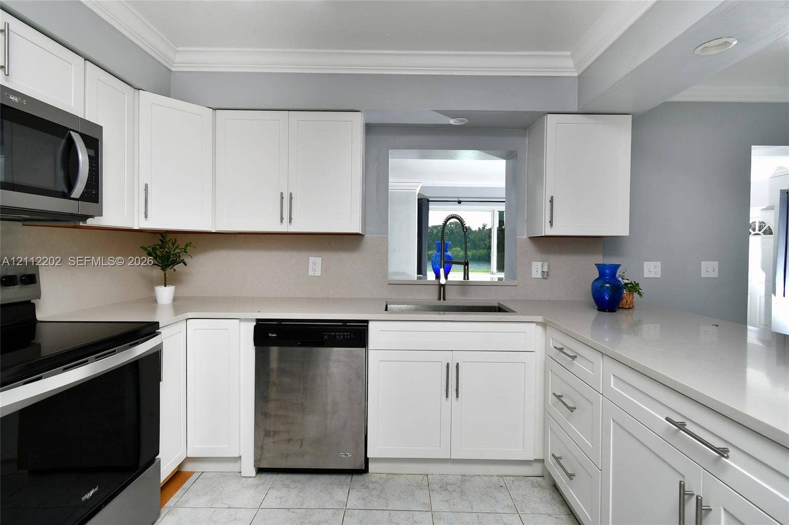 3233 Shell Lane, Labelle, FL 33935 Kitchen featuring white Shaker-style cabinetry, stone-finish countertops, stainless steel appliances, a deep undermount sink with a high-arch faucet, and crown molding
