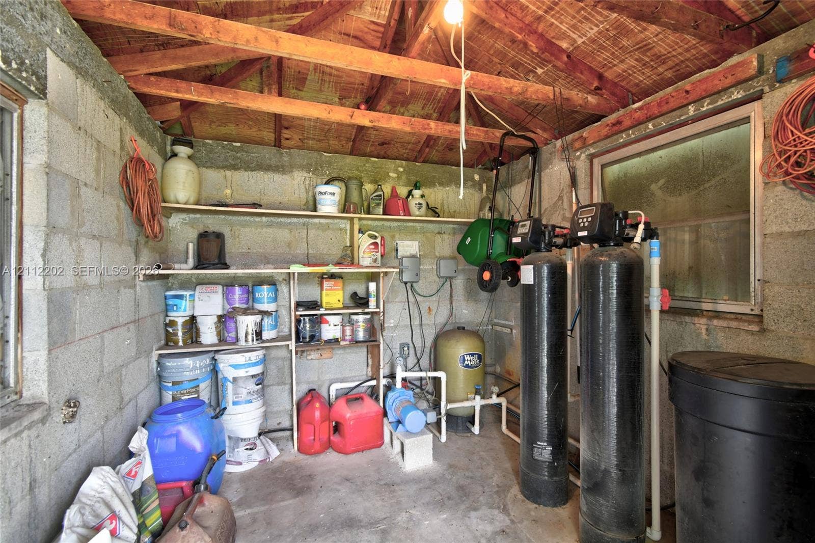 3233 Shell Lane, Labelle, FL 33935 Utility space featuring exposed beam ceiling, concrete block walls, built-in open shelving, and integrated water filtration system