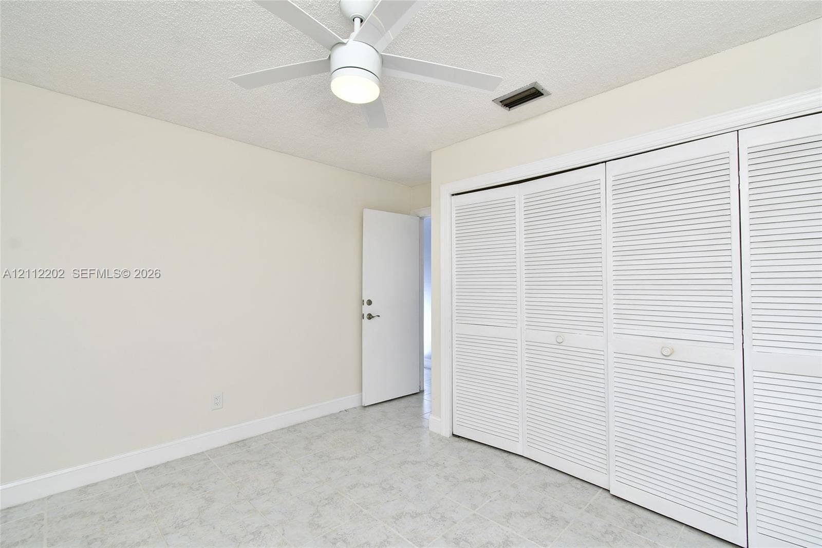 3233 Shell Lane, Labelle, FL 33935 Room featuring neutral-toned walls, tiled flooring, a ceiling fan with integrated lighting, and a triple-panel louvered closet door