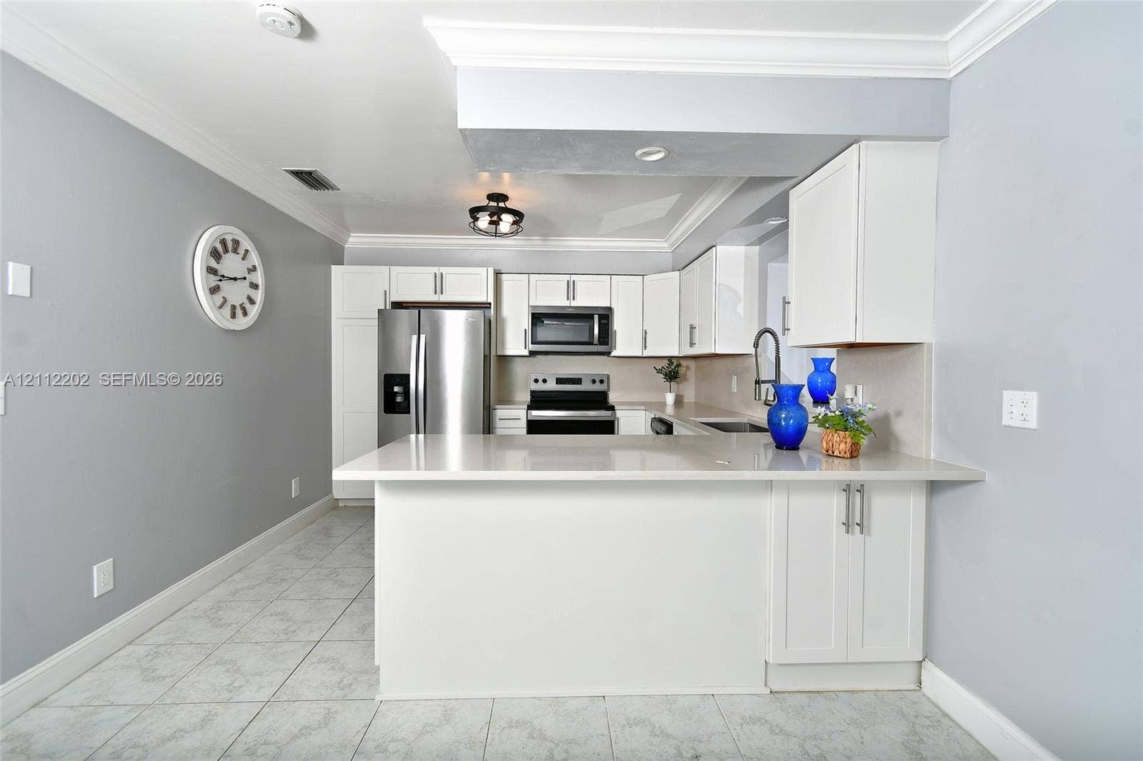 3233 Shell Lane, Labelle, FL 33935 Kitchen featuring white cabinetry, quartz countertops, stainless steel appliances, tile flooring, and crown molding