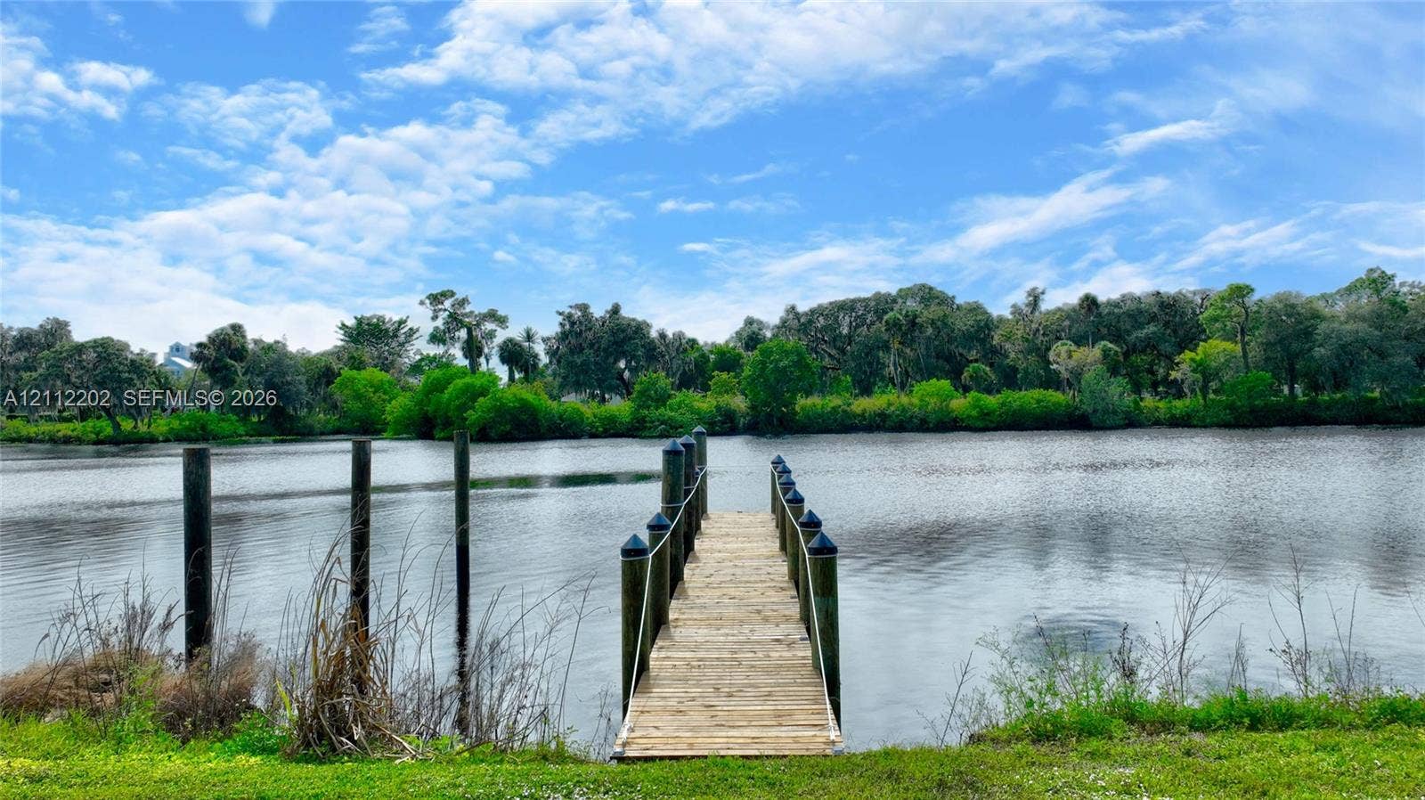 3233 Shell Lane, Labelle, FL 33935 Private wooden dock featuring pilings, rope railings, and direct access to a natural water feature surrounded by mature tree lines