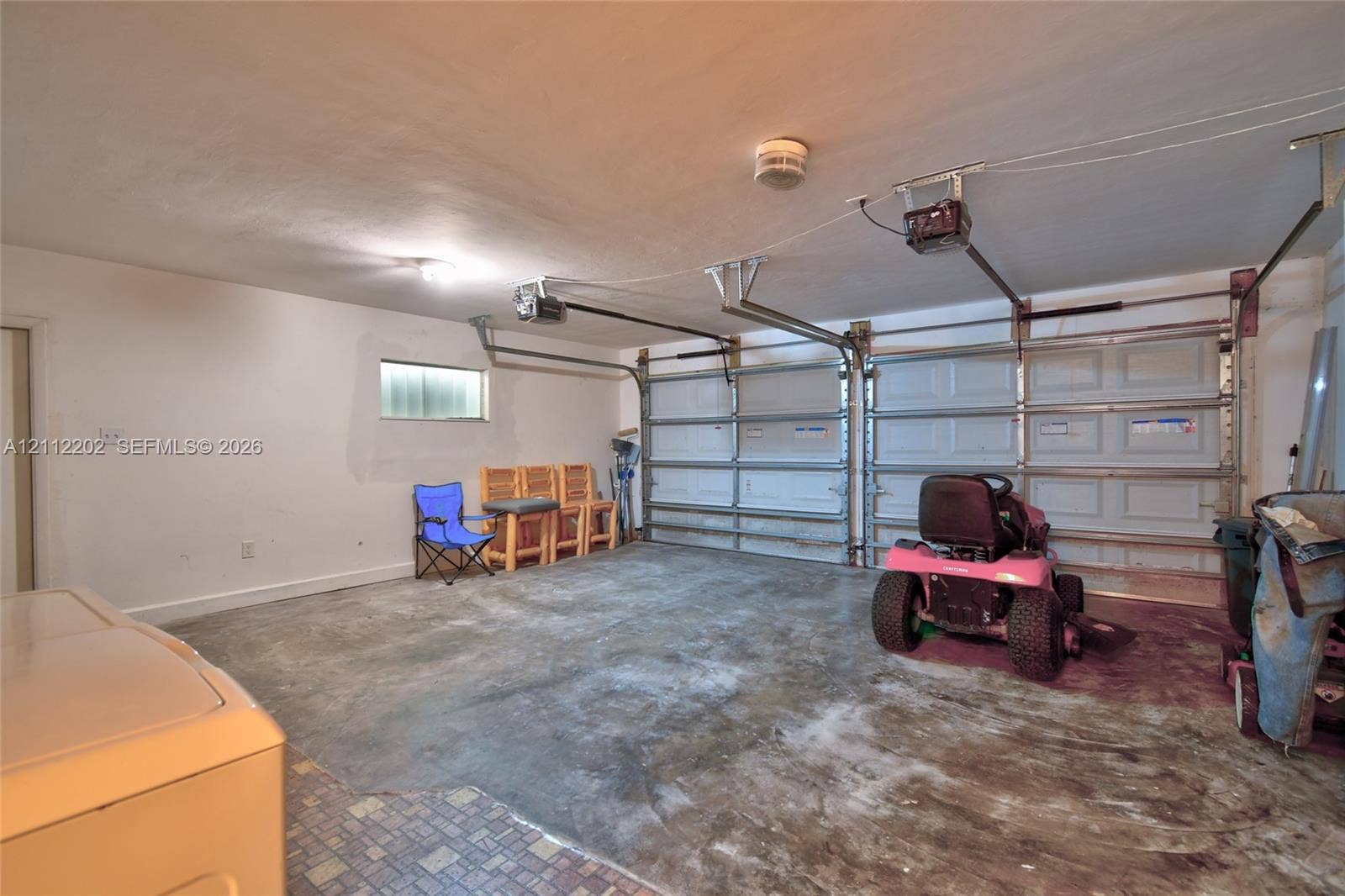 3233 Shell Lane, Labelle, FL 33935 Two-car garage featuring dual overhead metal doors, reinforced ceiling-mounted automatic door openers, and concrete flooring