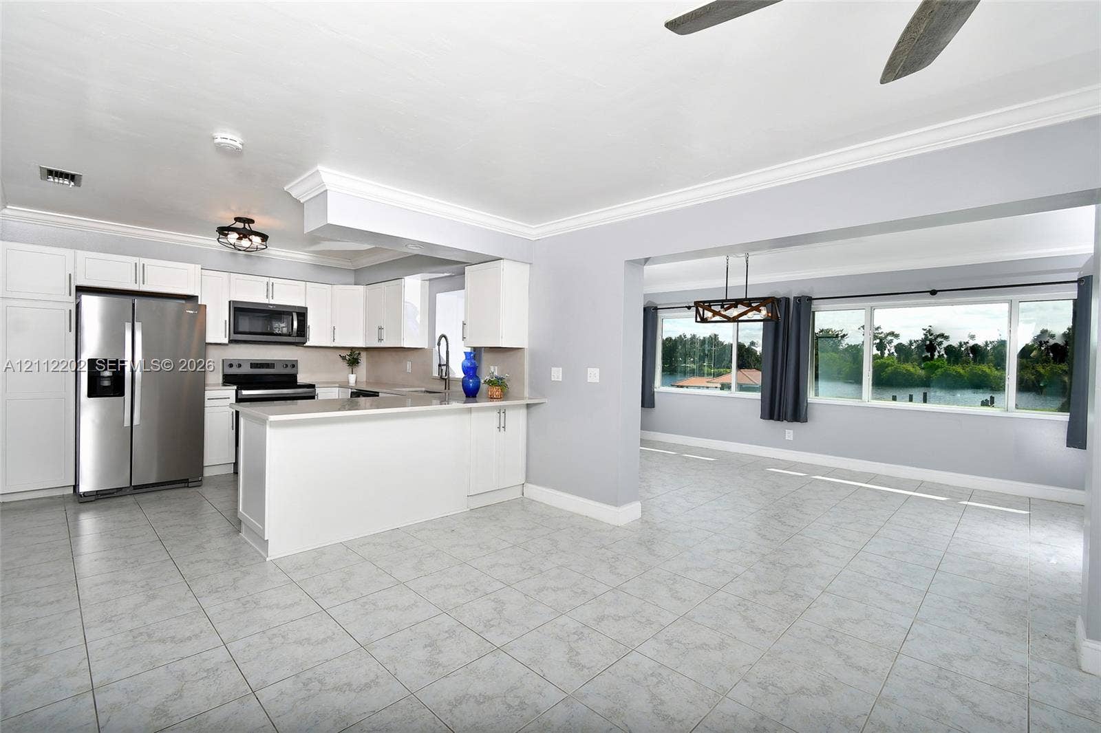 3233 Shell Lane, Labelle, FL 33935 Kitchen featuring white cabinetry, stone countertops, stainless steel appliances, and tile flooring, with large windows providing natural light