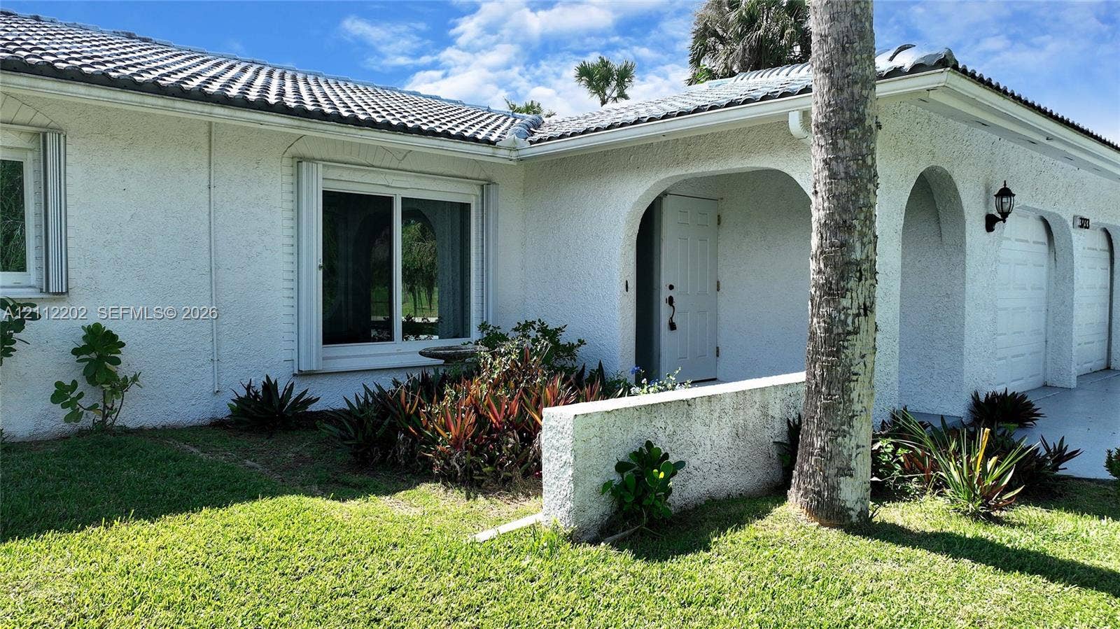 3233 Shell Lane, Labelle, FL 33935 Stucco exterior featuring arched covered entryway, tile roof, and built-in wall-mounted outdoor lighting